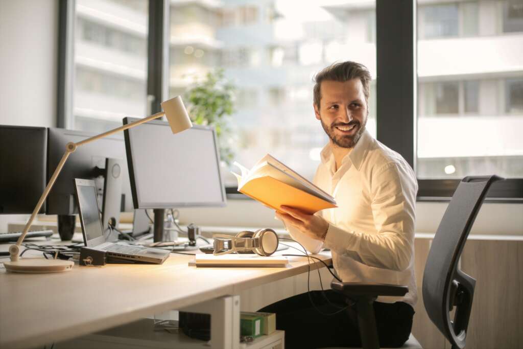 A person at a desk looking over their left shoulder and smiling.