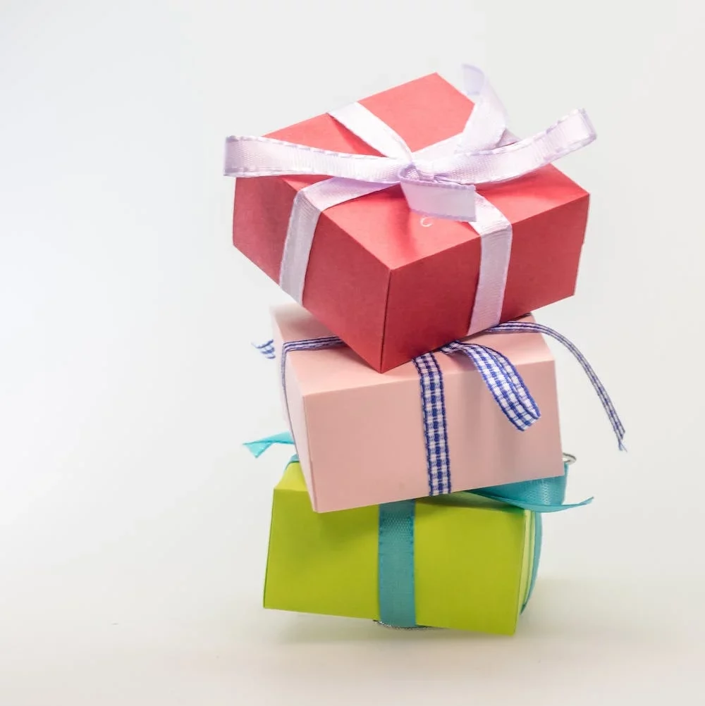 Stack of three realistic white gift boxes with pink ribbon and bow