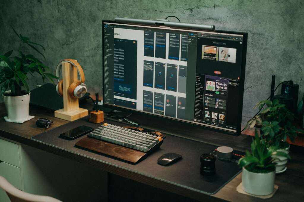 A work from home set up with a large monitor, wireless keyboard and headphones. 