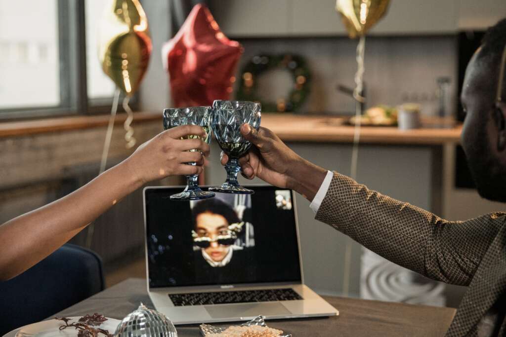 Two employees cheer during a remote virtual holiday party as a fun at work celebration idea