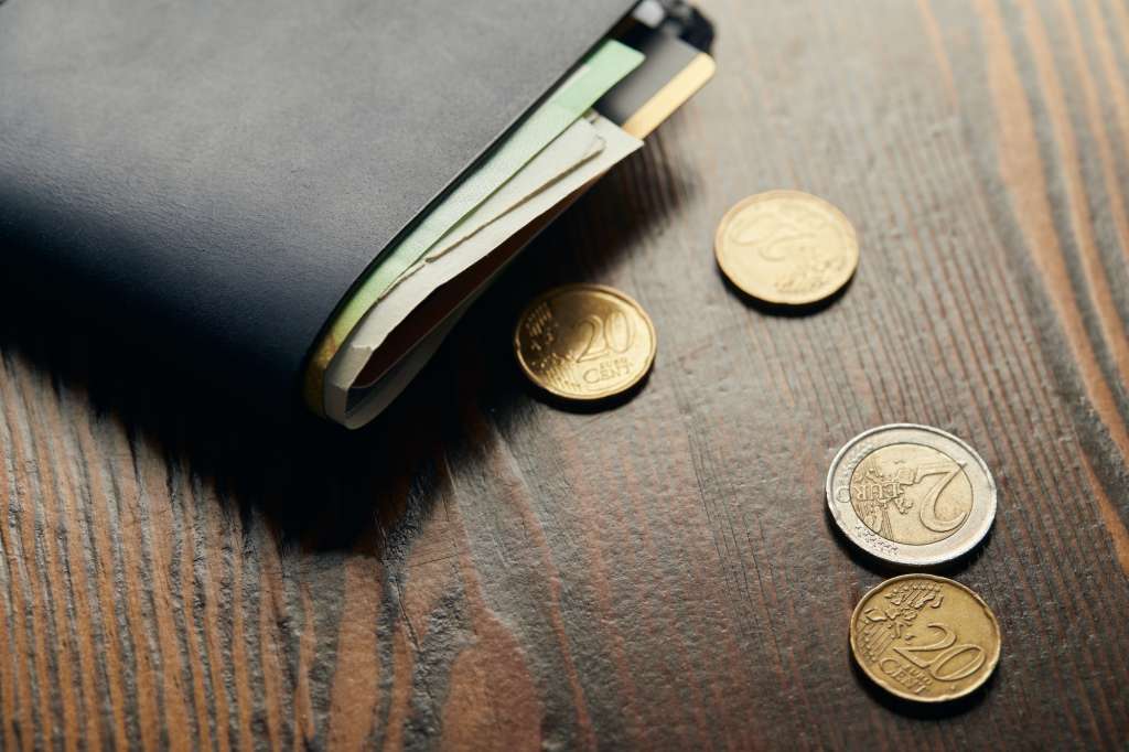 leather wallet with money and coins on wooden table
