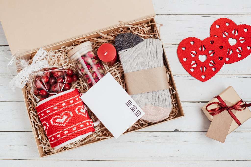 https://blogcdn.swagmagic.com/wp-content/uploads/2023/05/preparing-care-package-seasonal-gift-box-with-mug-candle-woolen-socks-and-christmas-ornament-1024x682.jpg