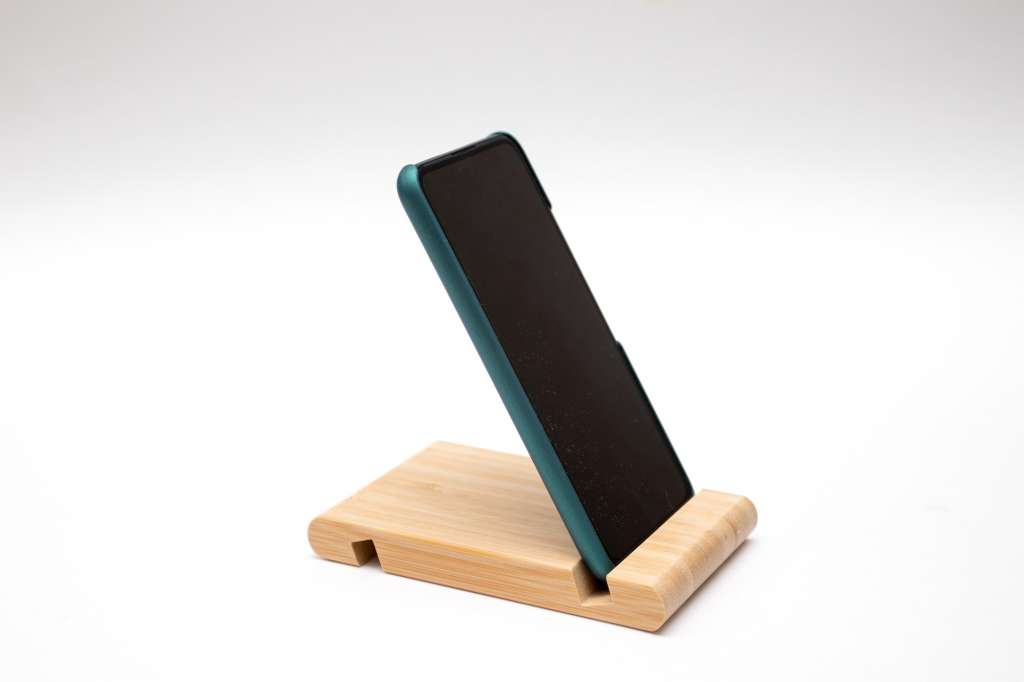 Wooden smartphone stand with smartphone on white background