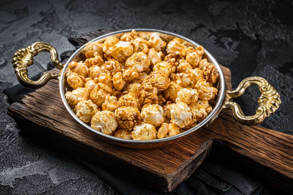 Caramel Popcorn in rustic bowl. Black background. Top view