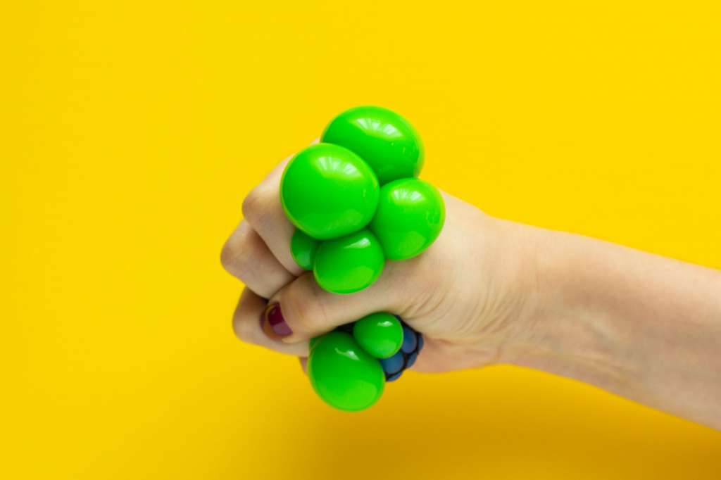 Green ball toy anti-stress in the girl's hand, close-up