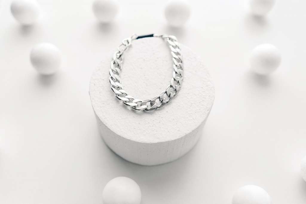 Imitation jewelry, silver bijouterie chain bracelet on white background. White podium.