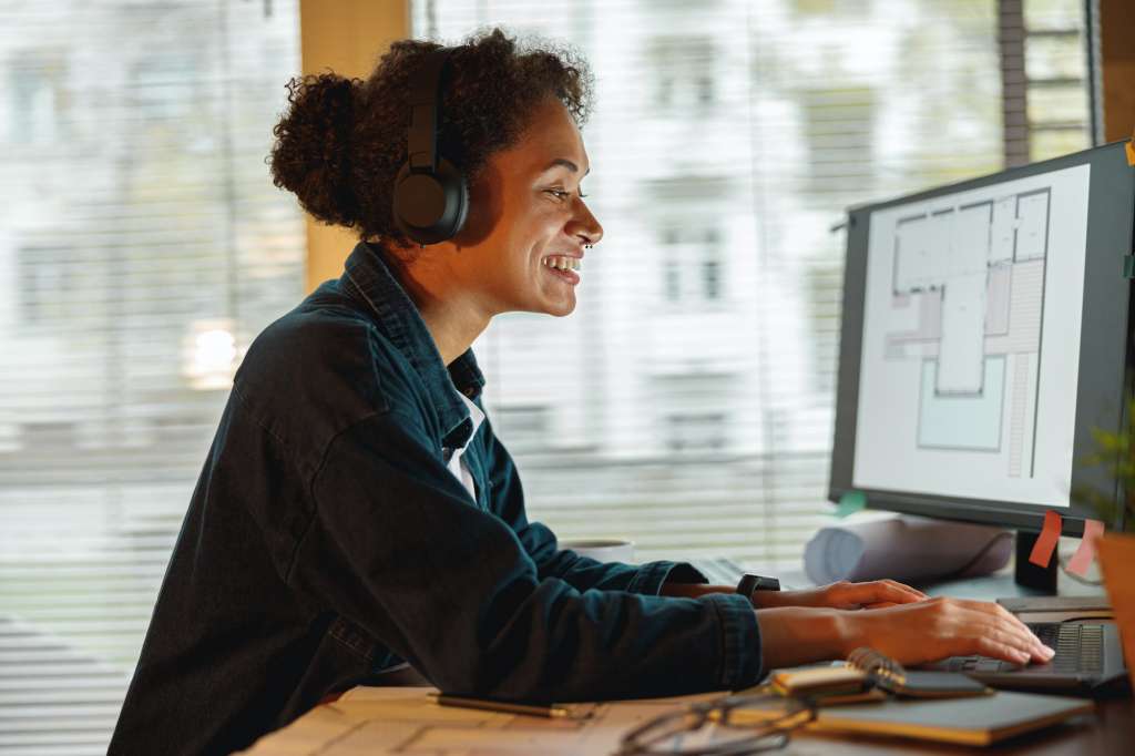Woman employee wearing headphones works in home office