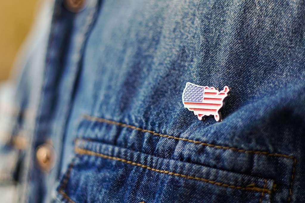 United State of America pin is pinned on blue jeans jacket. USA patriotism concept.