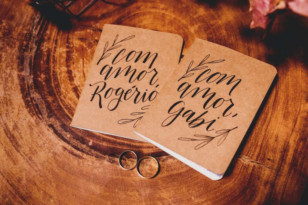 Beautiful shot of personalized hardcover couple notebooks of wooden paper color with wedding rings