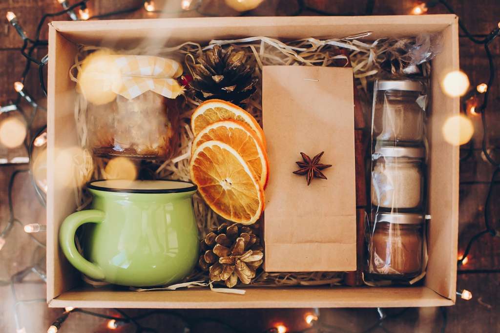 https://blogcdn.swagmagic.com/wp-content/uploads/2023/09/gift-box-with-tea-set-tea-cup-jam-spices-dried-oranges-in-box-with-christmas-lights-top-view-1024x682.jpg