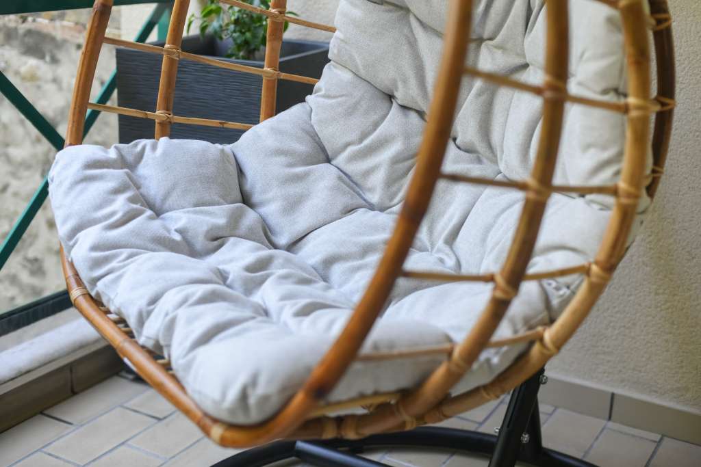 Bamboo chair with gray cushion hanging on the balcony