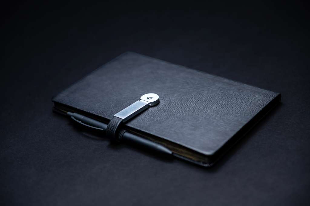 black planner or notebook with pen isolated on black background, mockup, copy space