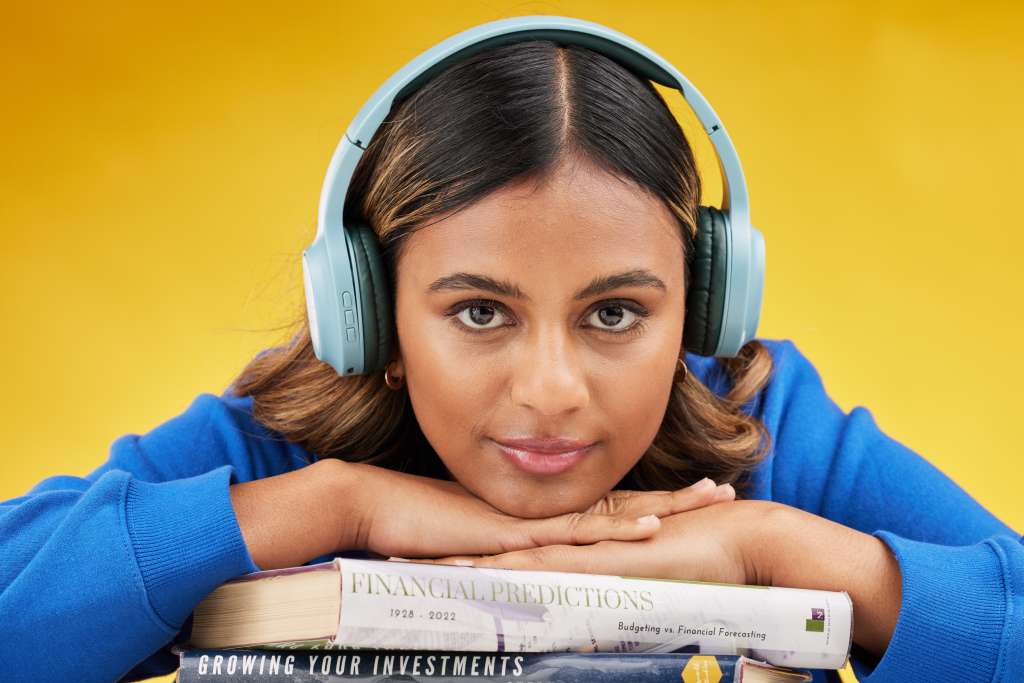Woman, student and studio portrait in headphones, books or listen to investing podcast by yellow ba