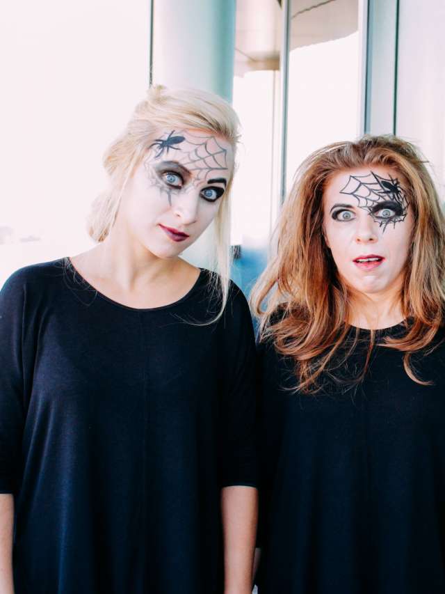 Halloween at the office. Young women dressed-up for Holloween. Painter spider webs on their faces