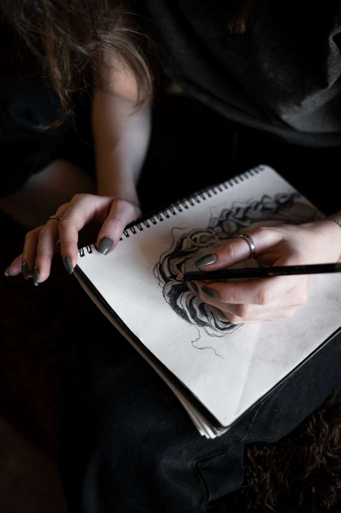 girl draws a sketch with a pencil in a sketchbook