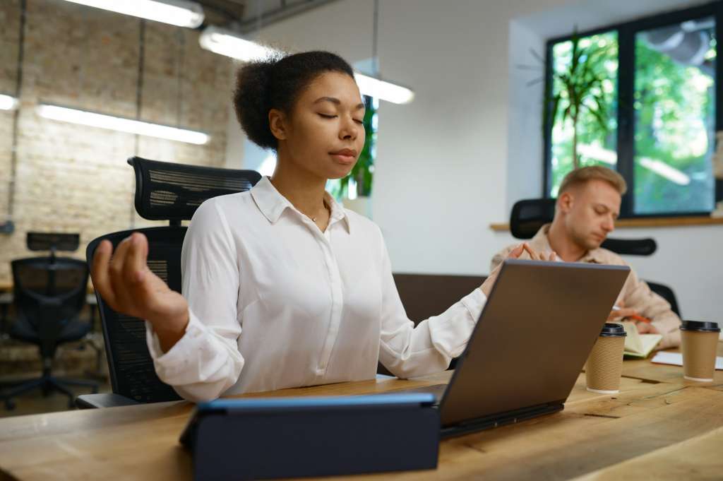Businesswoman office worker relaxing doing yoga front of laptop